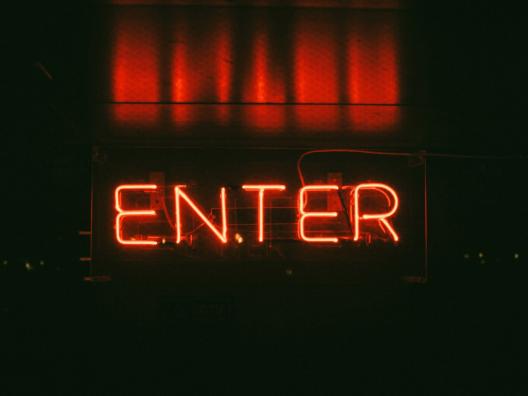 Dunkler Hintergrund mit rotem Schriftzug 'Enter' als Neonlicht