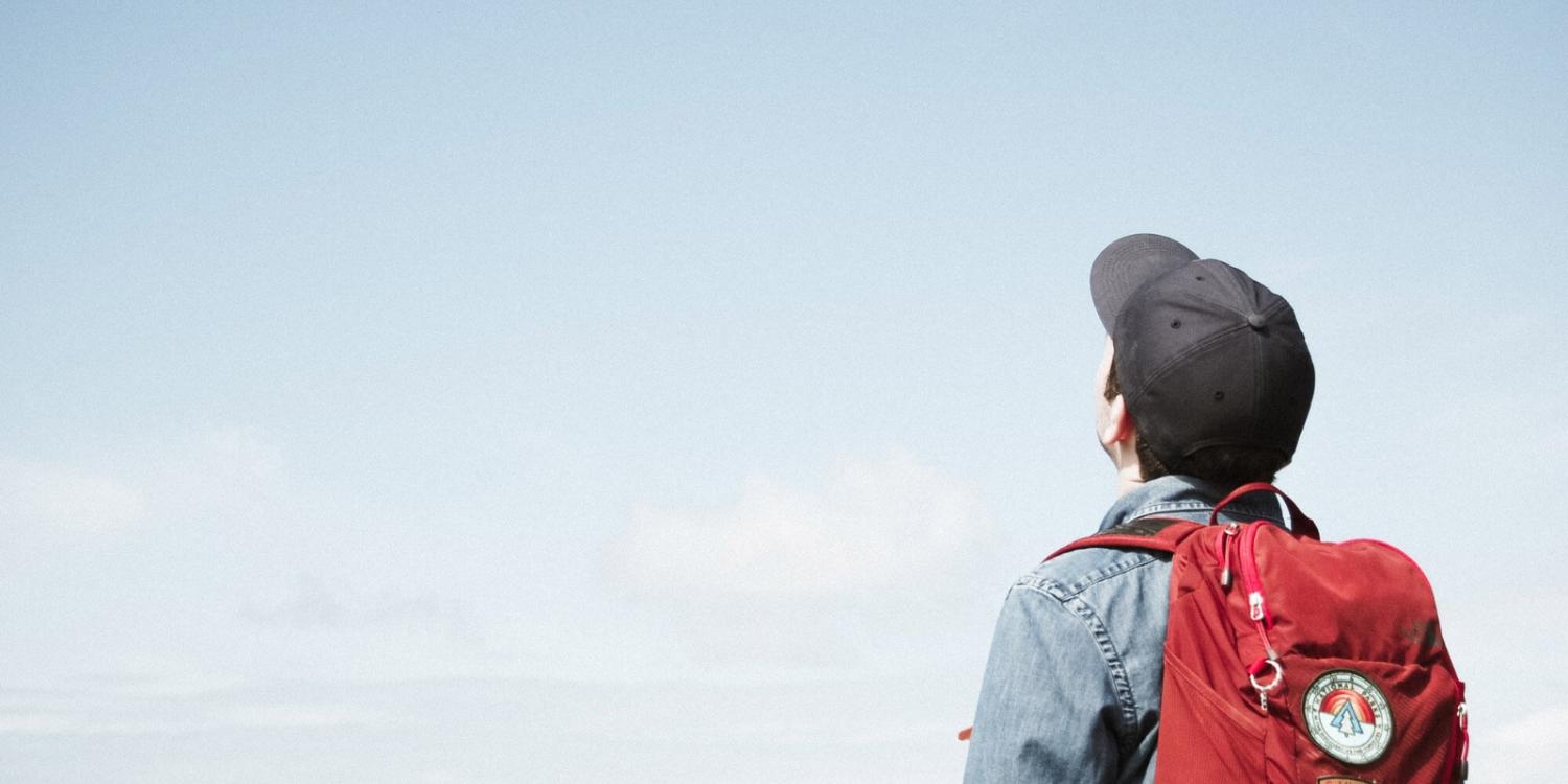 Mann mit Rucksack schaut in den Himmel